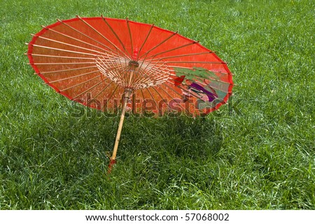 Red silk chinese umbrella on the green tree