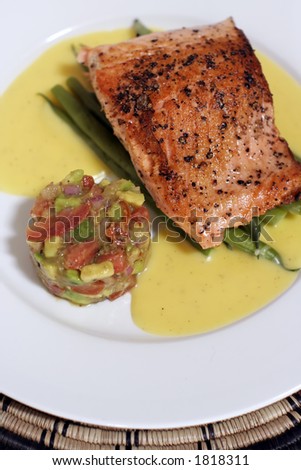 pan fried or sauteed salmon fillet on asparagus and lemon butter sauce, served with avocado, tomato and onion salsa. Flesh side up showing rich red \'grill\' effect and pepper.