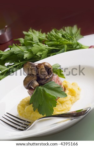 Lamb wrapped in bacon served with button mushrooms on butter, pumpkin and potato mash. Garnished with flat leaf parsley.