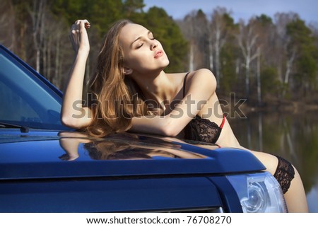 Beautiful woman in lingerie standing by the car and enjoy the sunshine and good weather
