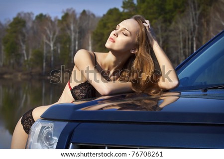 Beautiful woman in lingerie standing by the car and enjoy the sunshine and good weather