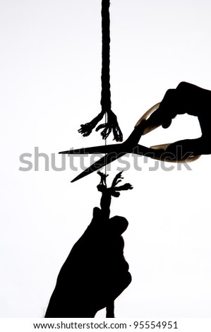 A hand holds a rope, scissors cuts the same string