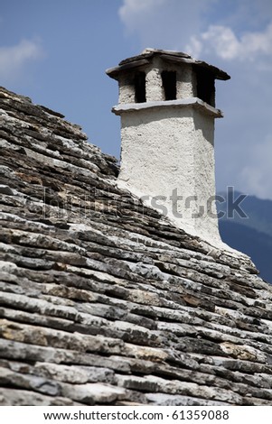 Old roof and chimney. Architectural detail of a chimney on an old roof made of stone