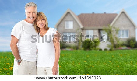 Senior couple near new home. Real estate background.