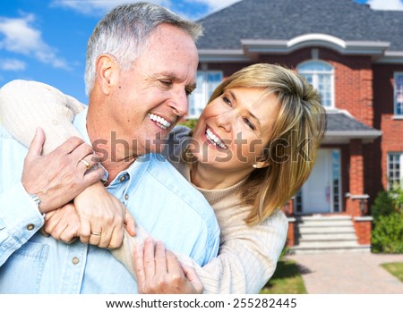 Happy senior loving couple over house background