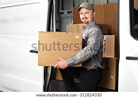 Young delivery man with parcel near cargo truck. Shipping service.