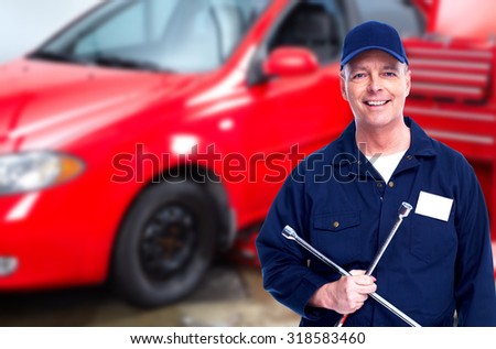 Smiling repairman with tire wrench in car repair service.