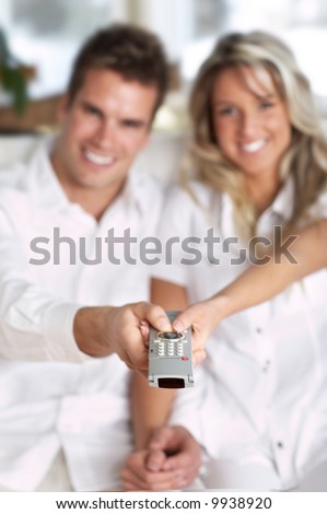 Young love couple smiling with TV remote control
