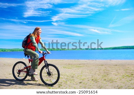 Young smiling  woman cycling near the lake