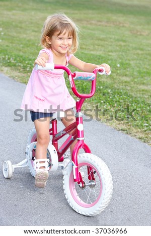 smiling little girl cycling  in the park