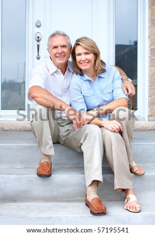 Smiling happy elderly seniors couple near the home