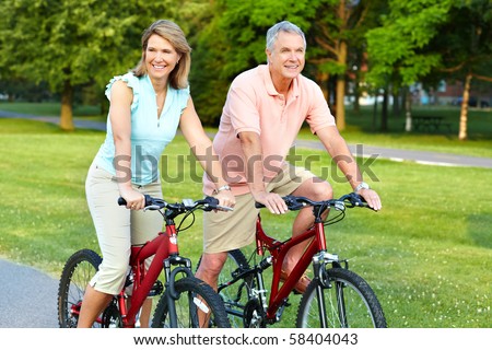 Happy elderly senior couple cycling in park