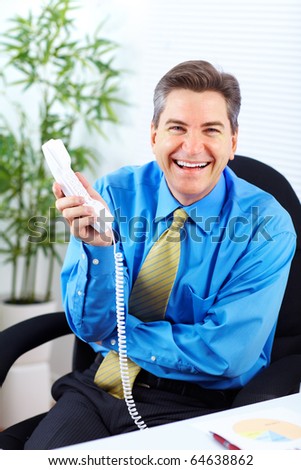Handsome smiling businessman calling by phone in the office