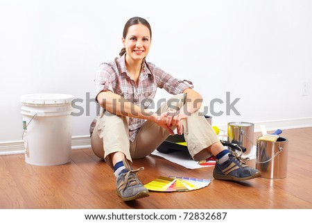 smiling beautiful woman painting interior wall of home.