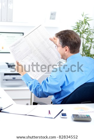 Mature business man reading newspaper in modern office.