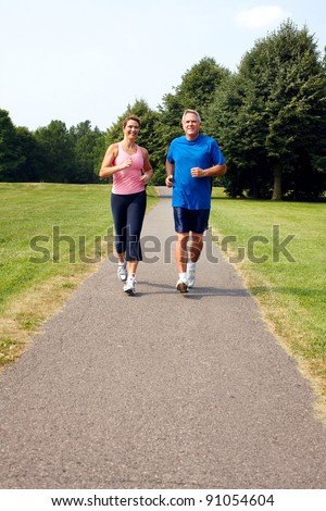 Happy elderly senior couple jogging in park.