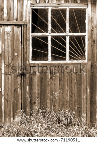 Old weather barn door and window with security bars in sepia tone