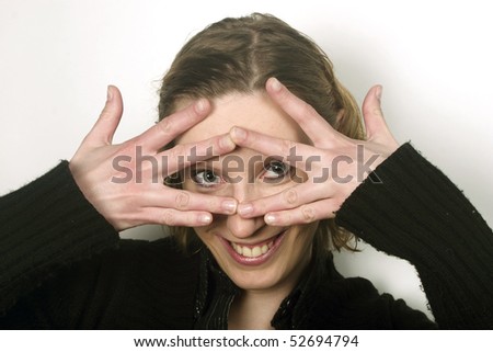 Blond young woman covering face with her fingers and peeking thorough them.