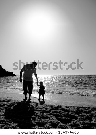 father and daughter playing on the beach at sunset