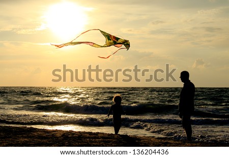 father and daughter flying kite at beach