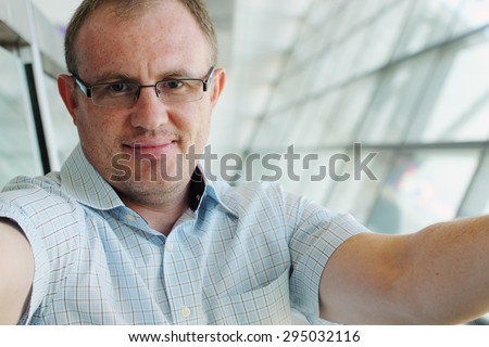 Selfie portrait of a handsome 35 years old man smiling indoor