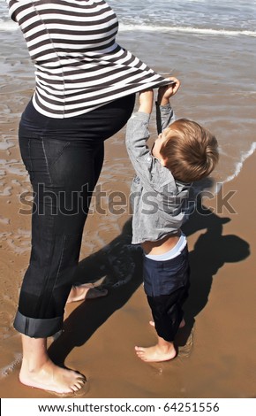 pregnant woman and her son on the beach