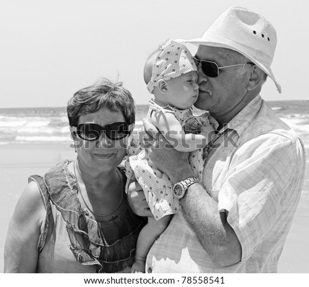 happy grandpa and grandma are holding a little granddaughter. Background - the sea.