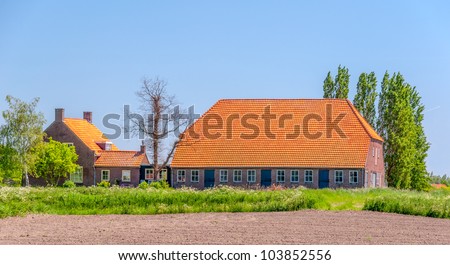 Large farm and barn with orange tiled roofs in the Netherlands.