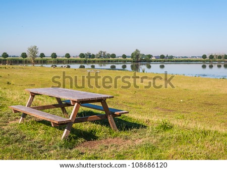 Wooden picnic table near a lake in a Dutch nature area.