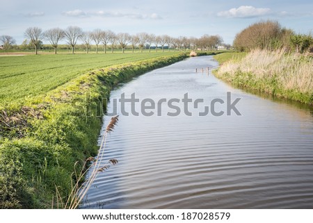 Small river meanders through the Dutch rural landscape in spring season.