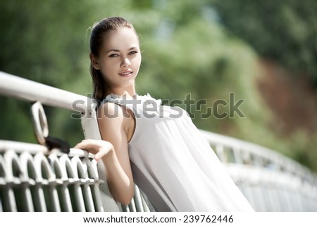 Beautiful brunette girl posing leaning against a white railing