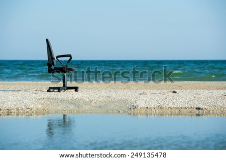 Concept illustrating the opportunity to work remotely, an office chair on the beach
