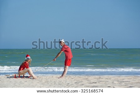 Concept: New Year on the beach. The girl in a red bathing suit and hat and New Year\
 guy with a pretentious person on the beach
