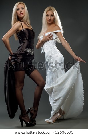 Two beautiful girls to models in evening cloth pose on gray background