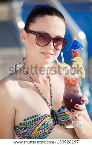 Happy woman with cocktail in swimming pool