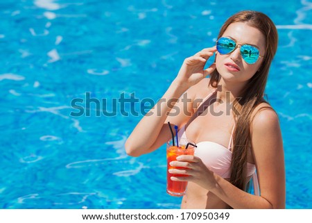 woman with cocktail in a swimming pool