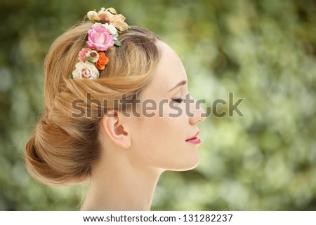 Beautiful young woman with flowers wreath in hair on natural green background