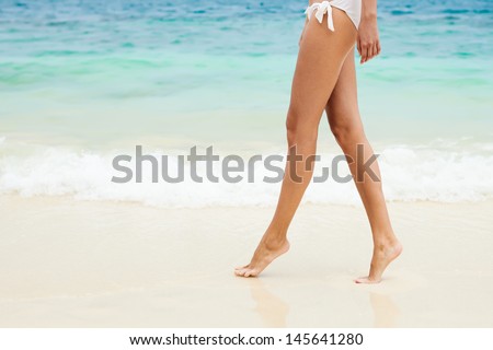 Walking on the beach. Close up on legs walking along the sea side