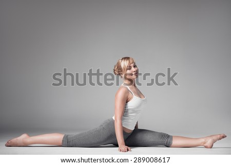 Full length of a young woman stretching body. Gray Background.
