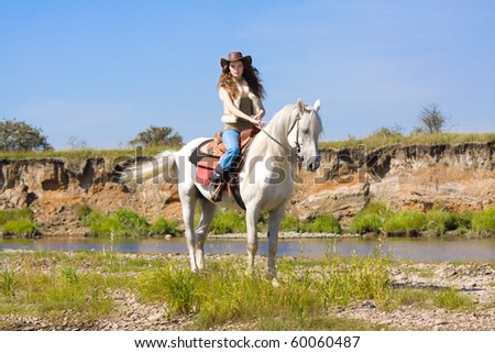 young cowgirl on white horse at the river