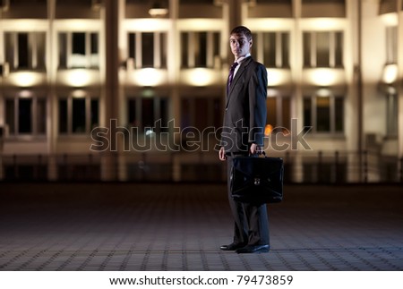 Handsome businessman with briefcase at night city in the background