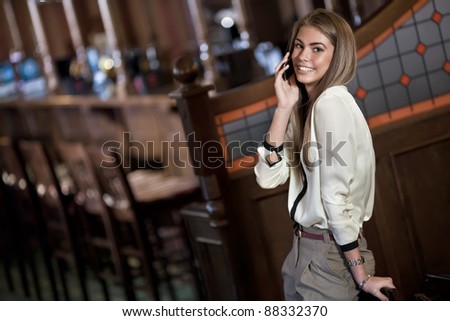 cheerful young woman talking on a cell phone in the interior of the bar