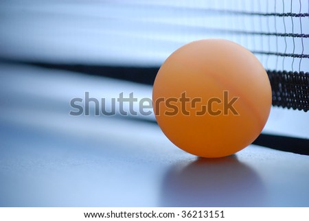 Orange table tennis ball on blue table with net