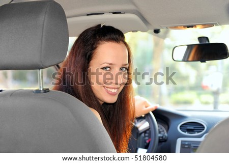 Portrait of young woman sitting in the car, looking back.