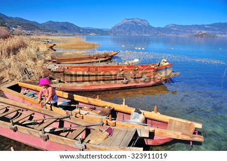 Lugu Lake, China Ã¢?? Dec 30 2013: Local Boat owner cleaning their boat.