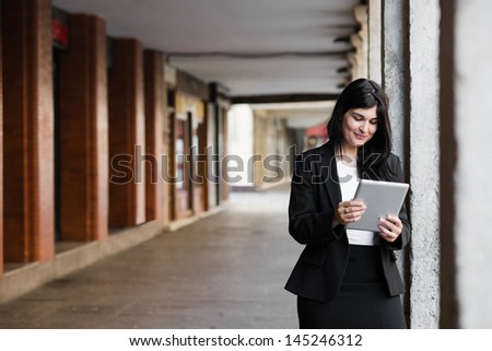 Pretty businesswoman surfing on the net in the street