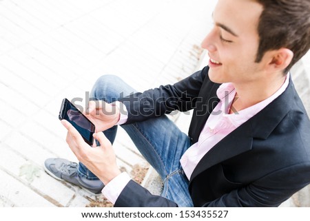 Young entrepreneur texting sit on stairs. Focus on his mobile