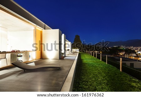 beautiful modern house in cement, view from the garden, night scene