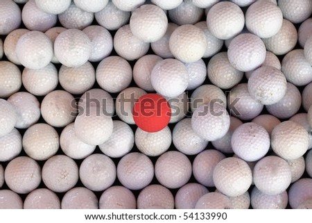 One Red Golf Ball Amongst a Sea of White Golf Balls.