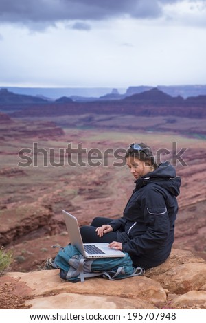 Girl Hiker on top of the mountain with her laptop computer
